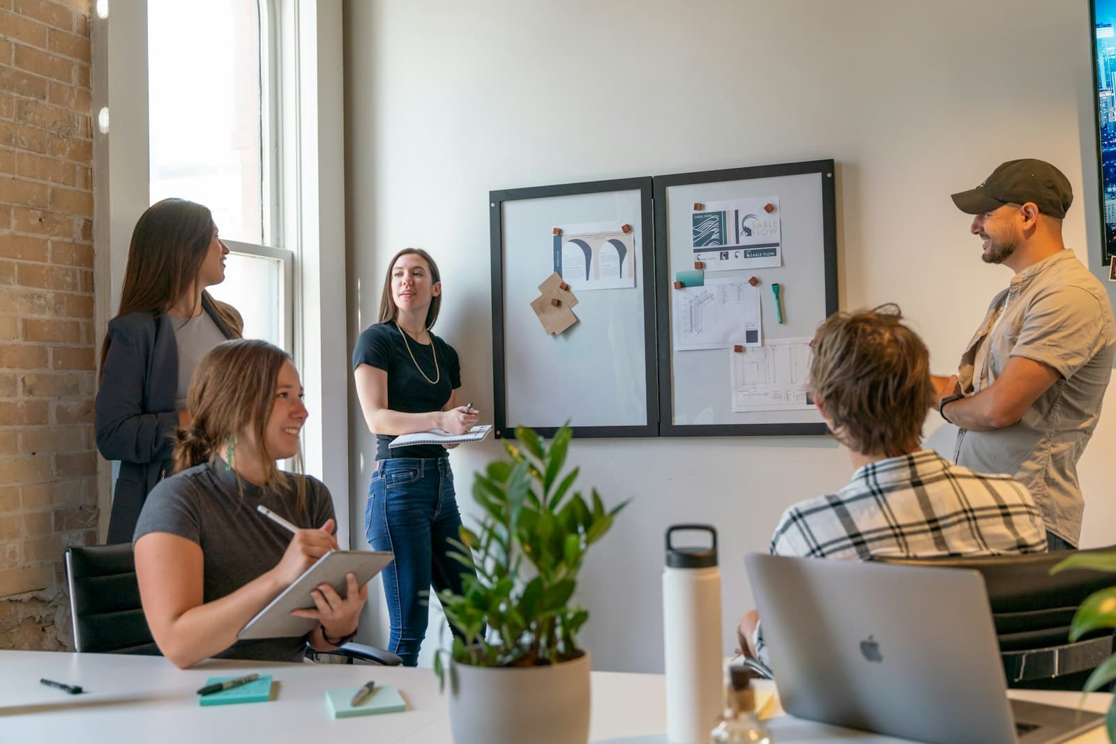 A founder team working through ideas at a pinboard in a sunlit incubator office