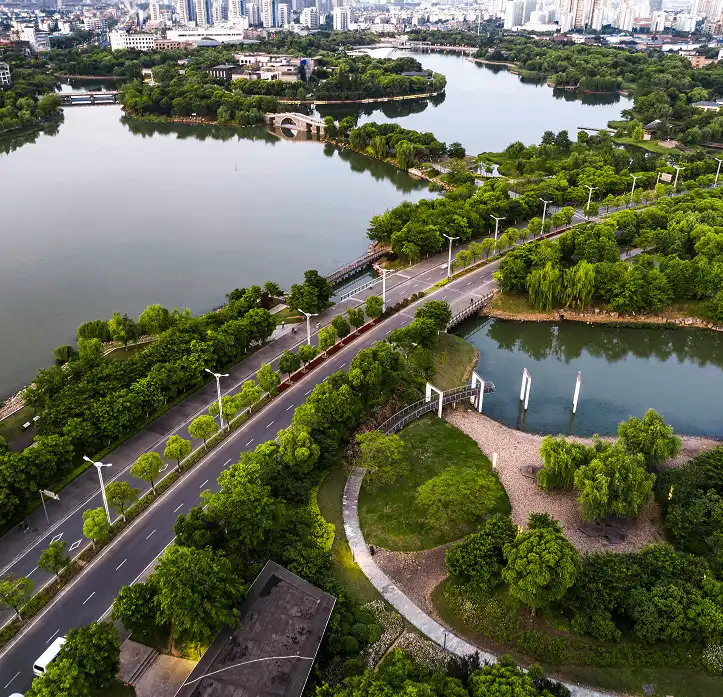 Aerial view of a city park with winding roads, dense greenery, and several lakes.