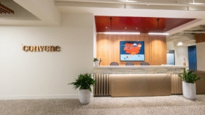 Modern office reception area with convene sign, abstract art, and potted plants on either side of the desk.