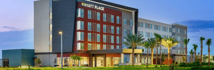 Modern Hyatt Place hotel exterior with multiple stories, large windows, and palm trees in front.