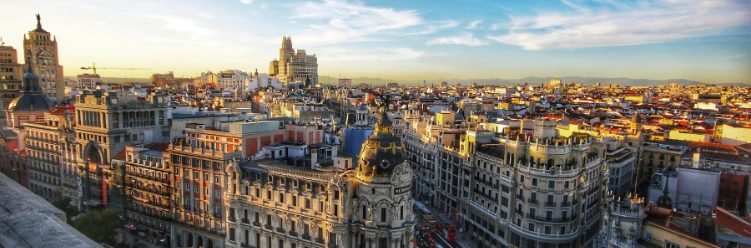 Panoramic skyline of central Madrid at sunset, showcasing ornate historic buildings and the iconic Metropolis Building.