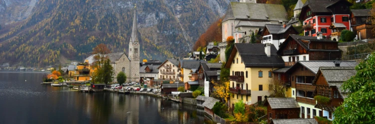 Picturesque lakeside village of Hallstatt in Austria, with colorful alpine houses and a prominent church tower backed by forested mountains.