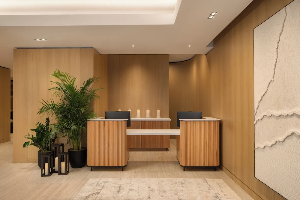 Modern reception desk area with wood paneling, potted plants, and decorative candles on the counter.