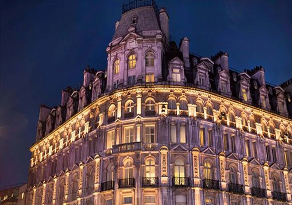 A grand historic building with ornate architecture illuminated by lights at night.