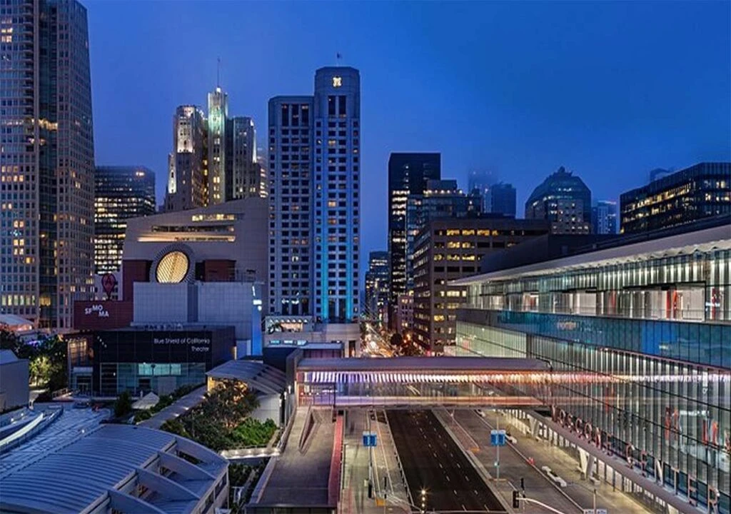 Downtown cityscape at dusk with modern skyscrapers and well-lit streets, showcasing urban architecture.