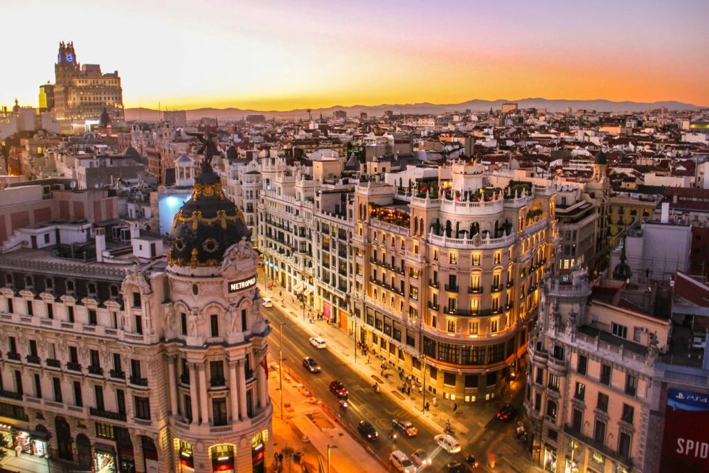 A sunset view of Gran Via in Madrid, with historic buildings and city lights starting to glow.