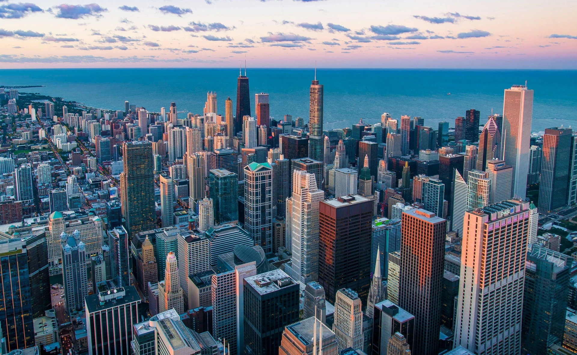 Aerial view of Chicago’s downtown skyline with skyscrapers and Lake Michigan at sunset.