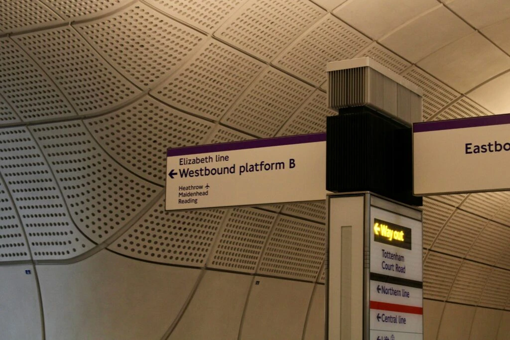 Sign for Elizabeth line Westbound platform B and way out at an underground station with a modern, curved ceiling.