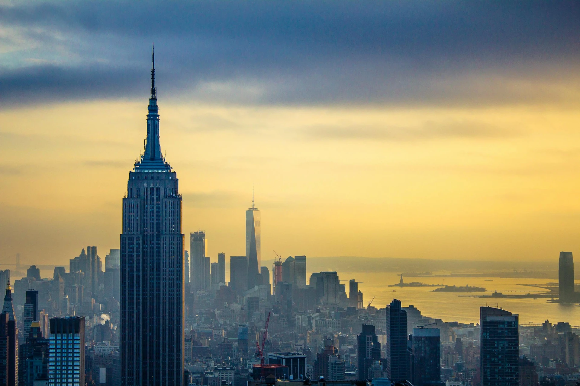 Empire State Building with a yellow sunrise sky over the New York City skyline in the background.