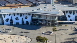A modern building with a wavy roof and irregular white patterns on its facade, seen from above.