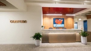 Modern office reception area with convene sign, abstract art, and potted plants on either side of the desk.