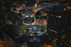 Night aerial view of a U.S. city downtown with illuminated streets and buildings decorated for autumn festivities.